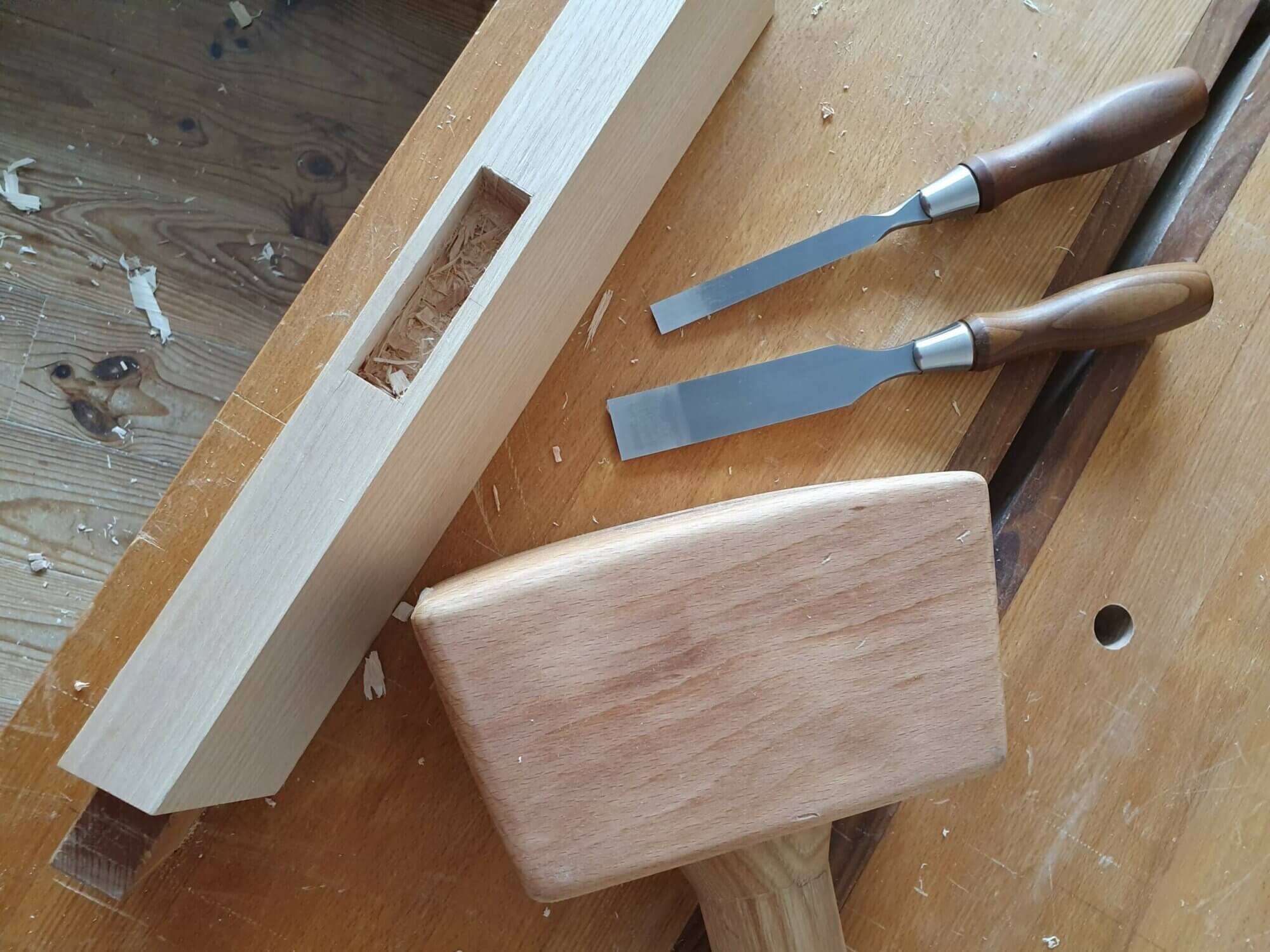 Un maillet, deux ciseaux à bois et une mortaise en cours de taille